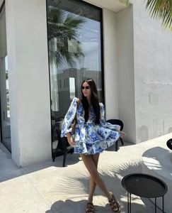 Detail of blue and white floral V-neck tiered dress with lantern sleeves and layered hem