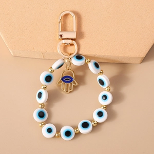 Detailed macro of golden Hamsa hand pendant and blue Evil Eye beads on key ring