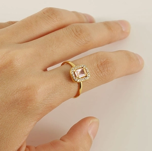 Macro view of 18K gold ring with pink emerald cut stone and pavé zircon details