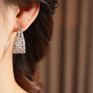 Dettaglio di un orecchino a forma di U placcato oro 18k con zircone indossato da una modella