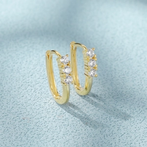 Macro shot of gold U-shaped S925 silver earrings set with three clear zircons