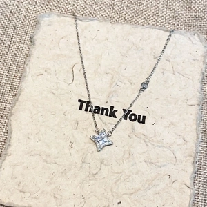 Detail showing a silver four-pointed star pendant with micro-pave crystals on a card