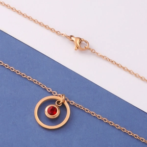 Close-up of rose gold necklace featuring a circular red gemstone in a double-ring pendant