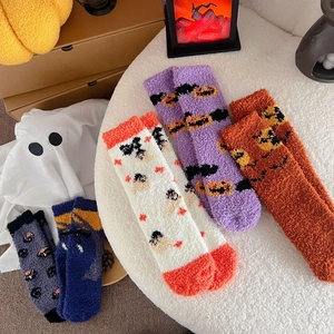 Flat lay of colorful Halloween fuzzy socks with pumpkin, ghost and bat patterns on white rug