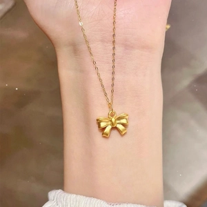 Elegant gold bow pendant necklace with a textured matte finish on a delicate chain