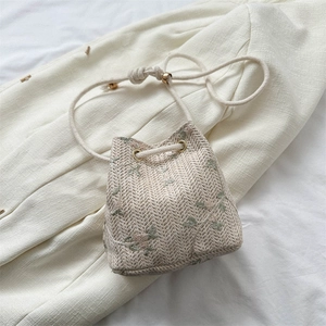 Woven straw bucket bag with floral embroidery and beige drawstring closure for summer