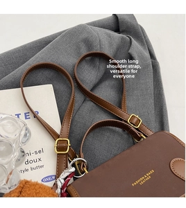 Detail of dark brown leather bag with adjustable strap and gold metal hardware