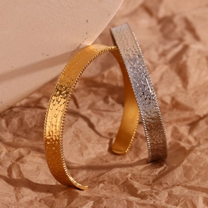 Macro shot of 18K gold and silver open bangles with hand-hammered texture finish