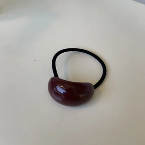 Close-up of a burgundy oval resin hair tie on an elastic band for chic daily styling