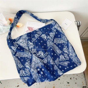Macro shot of large canvas tote bag featuring navy blue paisley pattern on a white surface