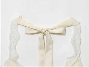 Detail of cream lace halter neck with satin ribbon bow tie on a backless top