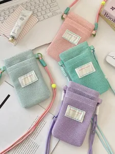 Colorful mesh crossbody phone pouches with adjustable ropes in a lifestyle desk setting