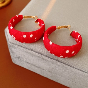 Dettaglio ravvicinato di orecchini a cerchio in tessuto rosso a pois vintage