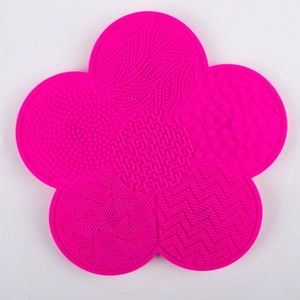 Macro view of flower-shaped rose pink silicone makeup brush cleaner mat with various textures