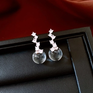 Detail shot of crystal glass ball drop earrings with zircon studs on black stand