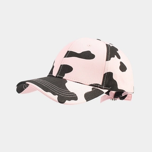 Detail view of pink and black cow print cotton baseball cap with curved brim and 6-panel crown