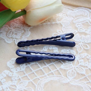 Detail shot of two dark blue gradient hair clips on elegant white lace background