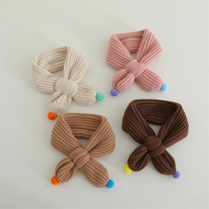 Detailed knit texture of children's winter scarves with colorful mini pom-poms
