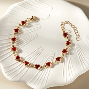 Detailed view of a gold chain bracelet with vibrant red heart charms and lobster clasp