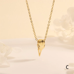 Detailed view of a golden bird skull pendant necklace with high polished finish on a chain