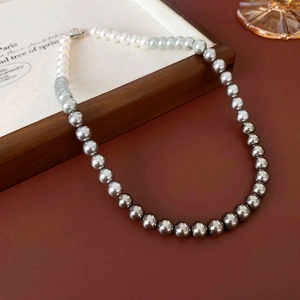 Close-up of gradient pearl necklace from white to grey on a vintage wooden surface
