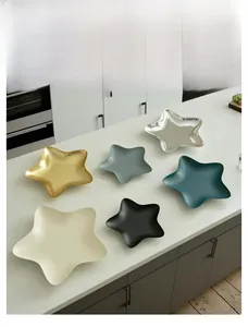 Detailed view of star-shaped metal trays in various matte and glossy finishes on marble