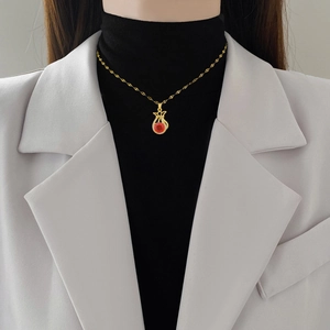 Elegante goldene Titahstahl-Halskette mit rotem Edelstein-Glücksbeutel an einem Modell