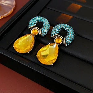 Dettaglio di orecchini vintage in bronzo a goccia con cristalli blu cielo e giallo brillante