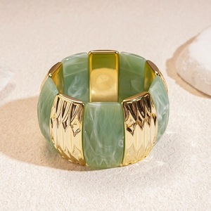Detail of green marble resin and golden wavy metal panels on an elastic bracelet