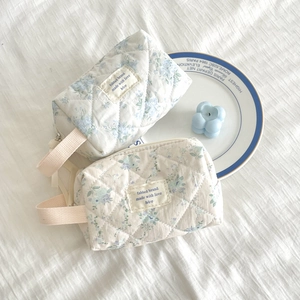 Close-up of quilted floral cotton makeup bag with blue flower patterns and sturdy hand strap