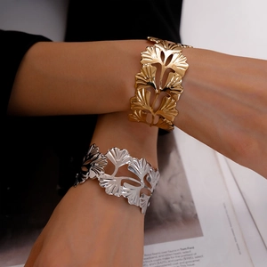 Gros plan de bracelets ouverts en métal doré et argenté avec motif de feuilles de ginkgo