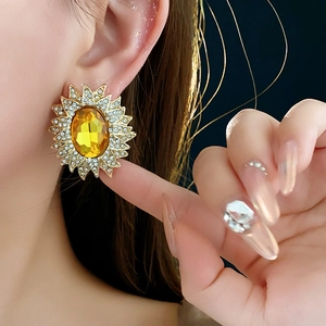 Close-up of vintage sunflower stud earrings with large yellow gem and rhinestones on model