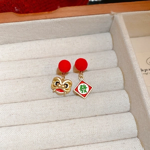 Detail of New Year earrings with red flocking ball, lion dance motif and Mahjong character