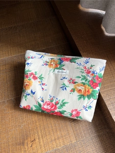 Nahaufnahme der Vintage-Kosmetiktasche mit Rosenmuster auf dunklem Holzgrund