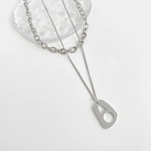 Collier double couche en argent avec pendentif géométrique sur fond blanc minimaliste