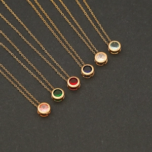 Close-up of gold necklaces with colorful round zircon pendants on dark background