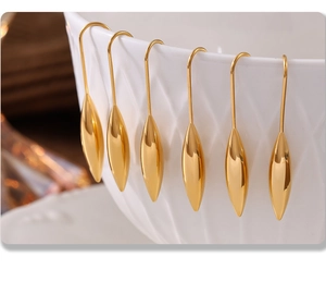 Macro shot of 18K gold plated teardrop hook earrings hanging on a white ceramic bowl