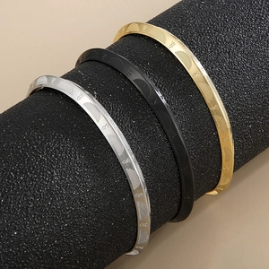 Detailed view of C-shaped titanium steel bracelets in gold, silver, and black finishes