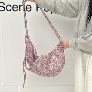 Detail of leopard print crescent bag featuring pink zipper and adjustable shoulder strap