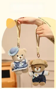 Detail of two plush teddy bear keychains in blue dress and denim overalls with lanyards