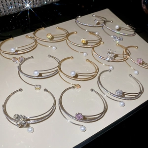 Close-up of elegant gold and silver bangles with zircons and pearls on display