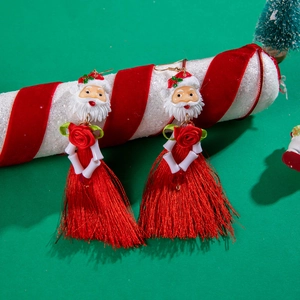 Detail of Christmas Santa earrings with red tassels and beads on festive background
