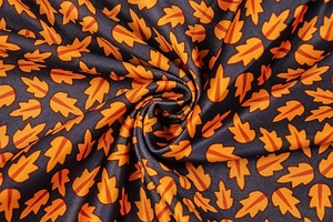 Macro shot of navy blue fabric with orange maple leaf print and twill texture detail