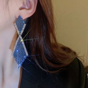 Detail of long rhinestone tassel earrings with blue crystals worn by a model