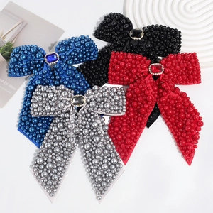 Detail of four satin bow hair clips in blue, black, red, and silver with pearls and rhinestones