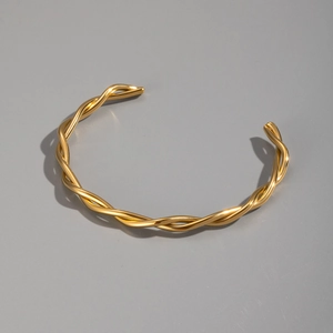 Detail showing the 18K gold plated twisted metal texture of the minimalist bangle
