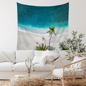 Detail of tropical beach tapestry with palm trees hanging above a modern sofa
