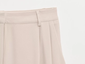 Gros plan du pantalon de costume beige avec taille plissée et passants de ceinture
