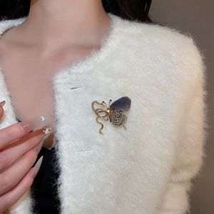 Detailed view of a rhinestone butterfly brooch pinned on white faux fur jacket