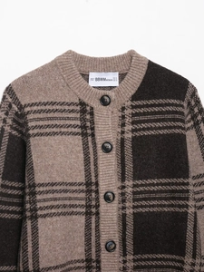 Close-up of brown plaid knitted cardigan with round neck and black textured buttons